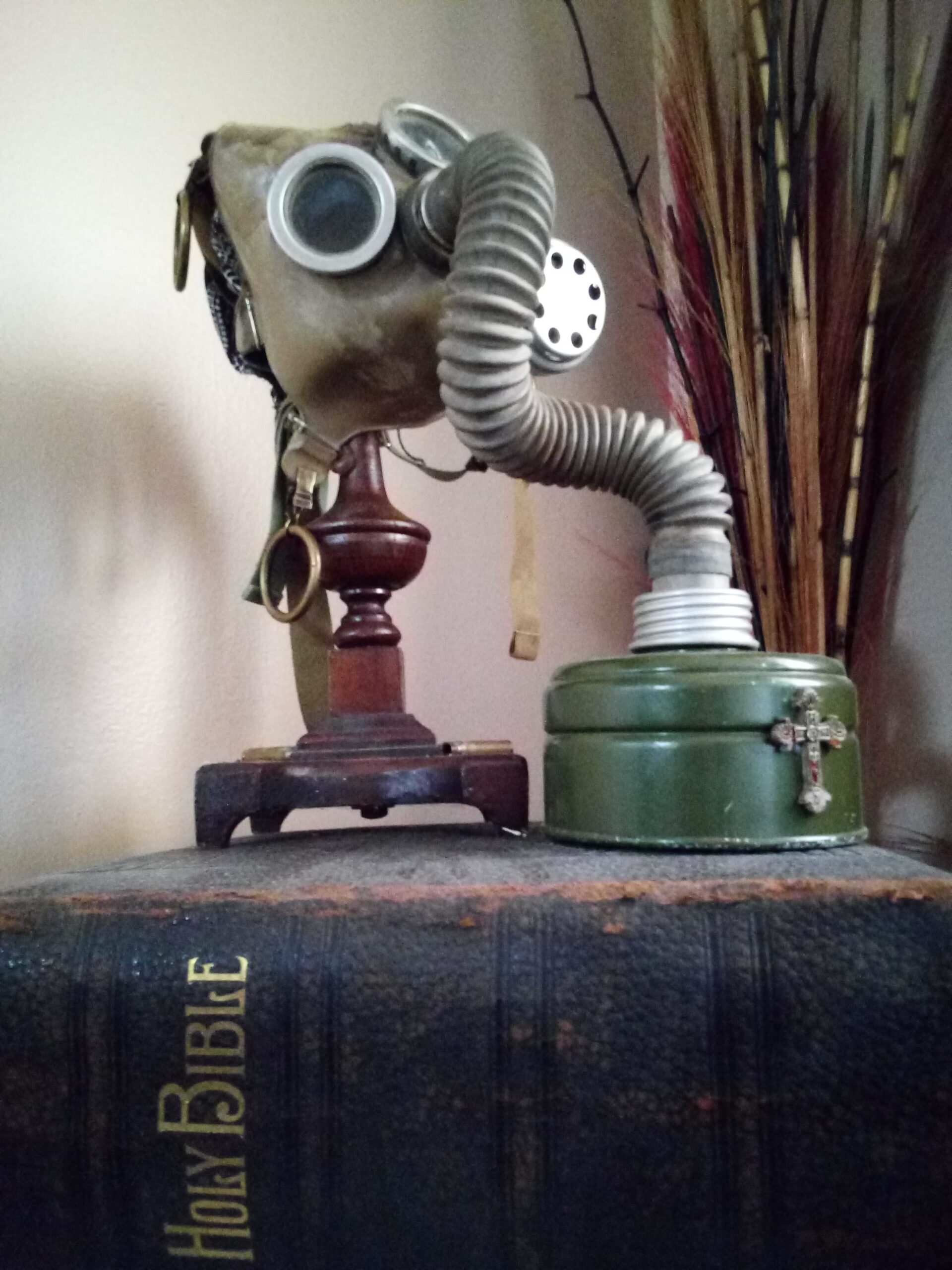 a gas mask painted with human blood on a small wooden display